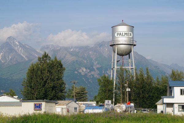 The Palmer Water Tower is towering above low buildings in the foreground, with snow-capped mountains in the distance.