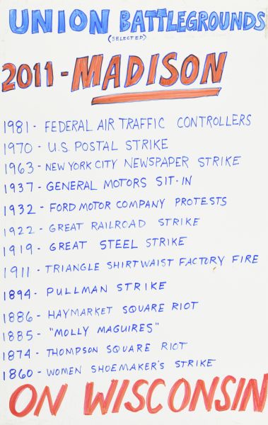 Handmade sign with blue and red text on white background. Text at top: "Union Battlegrounds (selected) 2011 — Madison." List of battlegrounds begins with: "1981 — Federal Air Traffic Controllers 1970 — U.S. Postal Service." List continues on backwards through the years, and ends with "1860 — Women Shoemakers Strike." Text at bottom: "On Wisconsin."