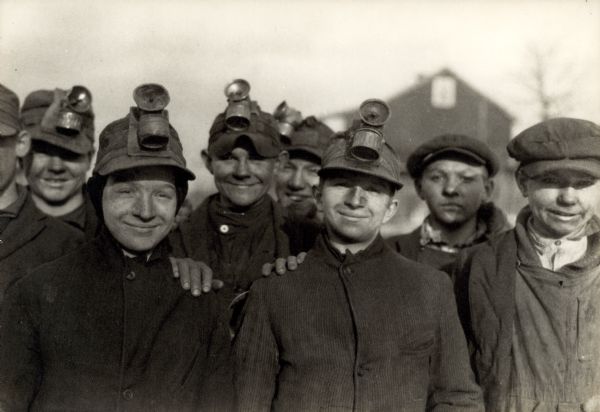 Group portrait of smiling miners, who are all young boys.