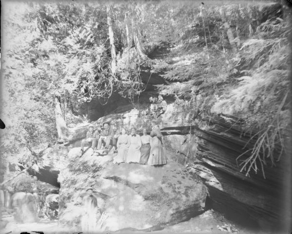 A group of three men and four women, probably members of the Von der Sump family, posing for a casual portrait on a rock formation at the Wisconsin Dells.