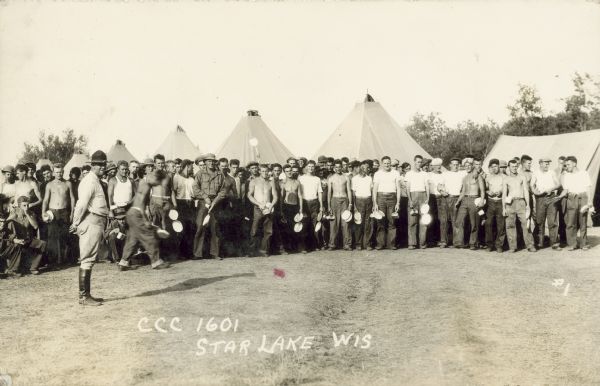 Caption on print reads: "CCC 1601 Star Lake Wis." Group portrait of men standing and holding camp eating utensils, including plates and mugs. Tents are in the background.