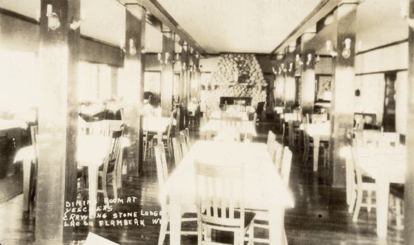 Interior view of the dining room. There is a large, stone fireplace on the far back wall. Caption in album reads: "Yeschek's."