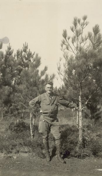 Man standing next to pine tree.