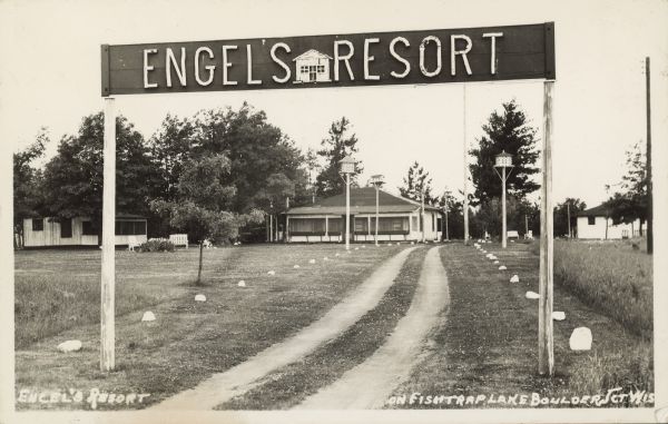 Engels Resort sign on posts above the entrance, with cabins in the background. Birdhouses on posts line the two-track drive. Caption reads: "Engel's Resort, located on Fishtrap Lake, Boulder Jct. Wis."