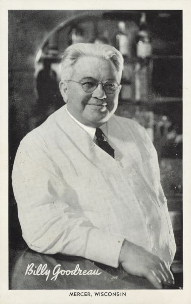 Portrait of Billy leaning on the bar. He is wearing a white jacket, and a dark necktie. "Caption reads: "Billy Goodreau, Mercer, Wis."