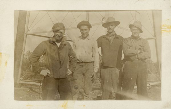 Group portrait of men standing at the base of what may be a forest protection lookout tower.