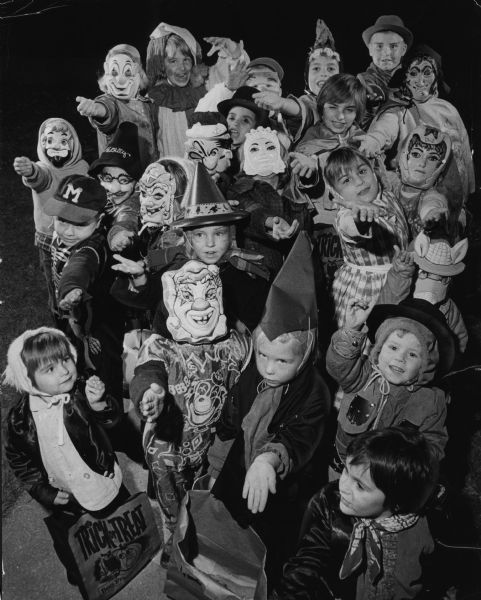 A group of children in Halloween costumes are reaching out their hands. Caption reads: "<b><i>Night for Beggars</i> Spooks and goblins prowled</b> the city's streets Wednesday night for the annual pre-Halloween trick or treat night. This group of youngsters 'worked' the 4500 block of N. 22nd and N. 23rd sts. An early check of one loot bag shared by a pair of beggars inventoried 16 candy bars, 45 pieces of loose candy, 17 pieces of bubble gum, 8 peanuts, 1 bag of popcorn and 2 apples."