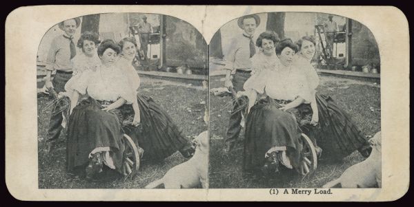 Stereographic image of a man pushing a wheelbarrow on which three women are seated. Caption reads: "(1) A Merry Load."