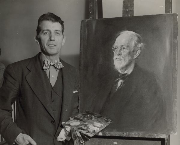 A man poses holding an easel, next to a portrait painting. The artist is Christian Abrahamsen, a Norwegian-born painter who was active in Chicago. The subject of the portrait is identified only as "Golighty."