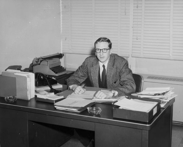 Portrait of Frank Adams, a journalist and organizer. He is sitting at a desk and holding a pen. This was taken while he worked for <i>The Virginian-Pilot</i> in Norfolk. Adams was also the author of a history of the Highlander Folk School, entitled <i>Unearthing Seeds of Fire: The Idea of Highlander</i>.