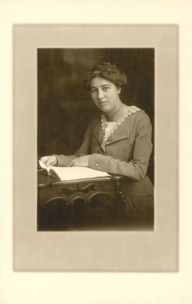 Seated portrait of Grace Adams Houghton, a University of Wisconsin 1906 alumnus. She was a high school teacher in Onalaska. She came from West Salem, where she was a member of Chapter number 64 of the Order of the Eastern Star. Reverse of photograph includes the dedication "To Charles McCarthy from Grace Adams. July 13, 1915."