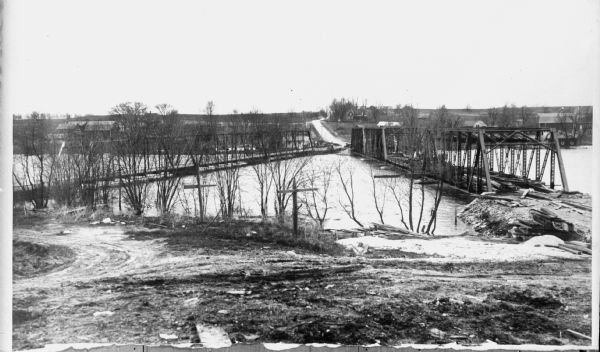 View towards two bridges. Article reads: "Highway 59, where it crosses the Rock River between Milton and Edgerton, is the scene of a bridge construction and highway straightening job that shows the difference between the methods of horse and wagon days and today. Sharp turns in the roads were then the accepted thing, and bridges were located where they would be shorter and cost less. Now we want no kinks in the road and place bridges so as to straighten the road, even though it be necessary to make the bridges longer and build greater length of approach. The new bridge on Highway 59 will make the road stright, eliminating a series of kinks like a great letter Z."