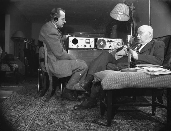 Caption reads: "W. H. Glover, field representative of the Society, in an interview with John Callahan, retired long-time Wisconsin state superintendent of public instruction, in which Mr. Callahan's reminiscences of "Sixty-four Years a Schoolmaster," are being recorded on a tape machine for later transcription to vinylite discs for permanent historical record."