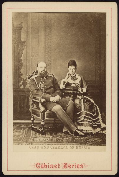 Carte-de-visite portrait in front of a painted backdrop of Tsar Alexander III and Tsarina Maria Feodorovna.