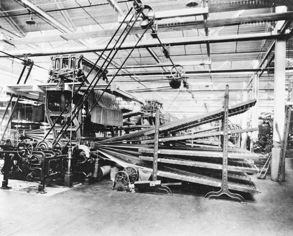 Large machine indoors. Caption reads: "Hartford, Conn. Weaving carpet material in the Bigelow-Hartford mill on a Jacquard loom."