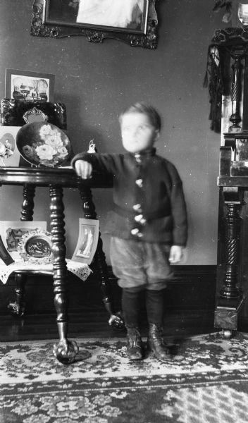 Portrait of a child, whose face is blurred by the exposure. Caption reads: "Madison, Wis. c. 1909-1935. 1821 Monroe Street. Adam Omen residence."