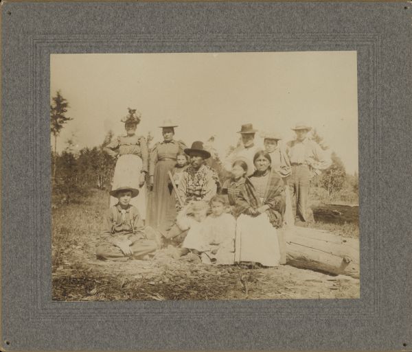 Outdoor group portrait of several people, identified collectively as "Pillager [Band] Ojibwa."