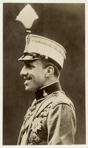 Waist-up profile portrait of King Alfonso XIII of Spain, who is wearing a uniform. Caption reads: "(100) King Alfonso's Throne Shaky. Conditions in Spain are reported to be steadily growing worse, and it is believed the fall of the monarchy is but a matter of a few days. The country appears to be in the throes of a revolution, the leading parties in the nation having joined the opposition to the king."
