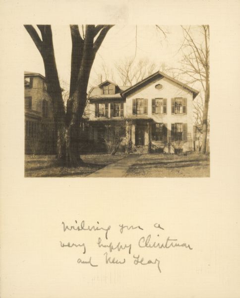 View of a house with a tree in the front yard. Caption on front reads: "Wishing you a very happy Christmas and New Year." On the reverse is written: "Wouldn't I like to see you coming up this walk! Love from K. A. [Katharine Allen]." This is the home of William Francis Allen, professor of ancient languages and history at the University of Wisconsin, located at 228 Langdon Street.