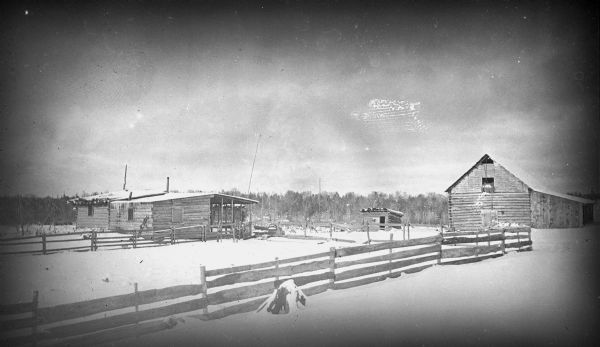 Exterior view of Deitz cabin and barn, fences, and other outbuildings in winter, about two weeks after shooting of deputy. No members of Deitz family were present, but stock were still in barns, cared for by two young men. The shooting was done from the hayloft through a hole made in the roof.<p>John Deitz and his family and the Cameron Dam incident in which Deitz and a Sawyer County, Wisconsin, posse engaged in a shoot-out in 1910.