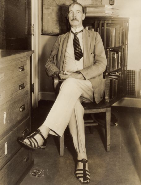 Portrait of a man seated in an office. Caption reads: "HE FAVORS MORE STUDENT MARRIAGES. Prof. Edward Aylesworth [sic] Ross, widely known sociologist of the University of Wisconsin, has just returned from a study of family relations in Tahiti and other islands and has brought the prescription of more student marriages as an aid to American family life. Ross, shown here in the sandals he has adopted since his visit to Tahiti, has asserted that the marriage of John College and Betty Coed with the parents consent and proper economic backing is a wholesome arrangement and should be encouraged."