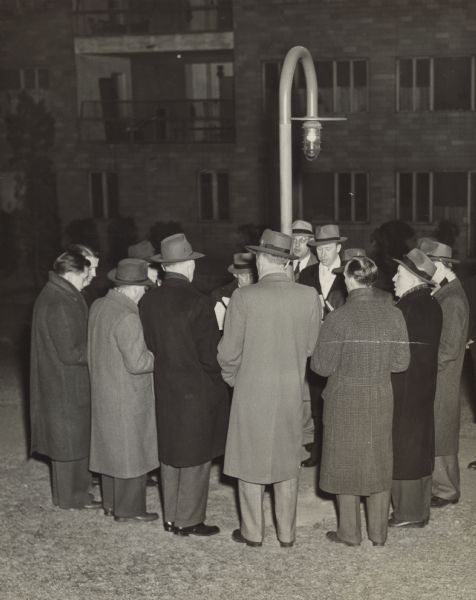 A group of men encircle a lightpost. A caption identifies them as "Hosiery Union housing project men's choral group."