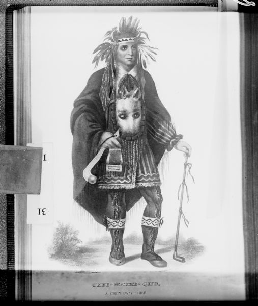 Painted portrait of a man in a feathered headdress with buffalo horns. He is wearing a cloak with an animal face in front, and he is holding a war club and a long peace pipe. Caption identifies him as "Okee-Makee-Quid, a Chippeway Chief."