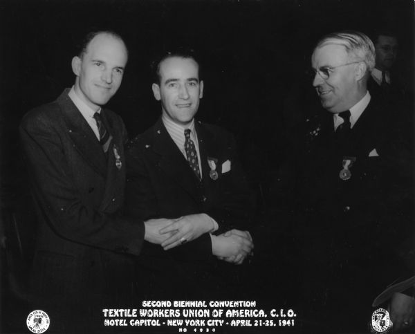 Three men are posing shaking hands. Caption reads: "Second Biennial Convention. Textile Workers Union of America. C.I.O. Hotel Capitol - New York City - April 21-25, 1941. No. 4934." Includes seals for "Amer. Fed. of Photo Emp. Union Local 21314" and "Knickerbocker Pictures."