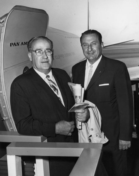 Two men stand outside the door to a Pan American airplane. Caption reads: "Leaving New York's Idlewild Airport on way to international conference in Sweden are TWUA's William Pollock (left) and J. Harold Daoust."