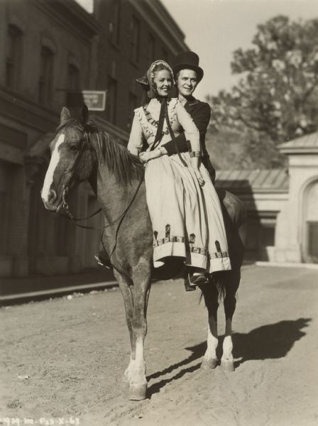 A man and actress Alice Koerner sit on a horse on the set of the 1939 film "Zenobia." 
