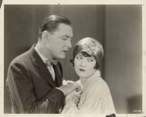 David Lacy (Kenneth Harlan) holds the hands of Connemara Moore (Marie Prevost) and looks longingly at her in a scene from the 1925 film "Bobbed Hair".  She looks away from him.