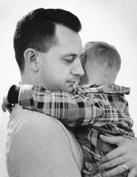 A father is holding his young son in his arms.