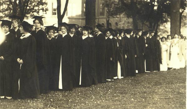 Group of graduates in robes lined up outdoors.