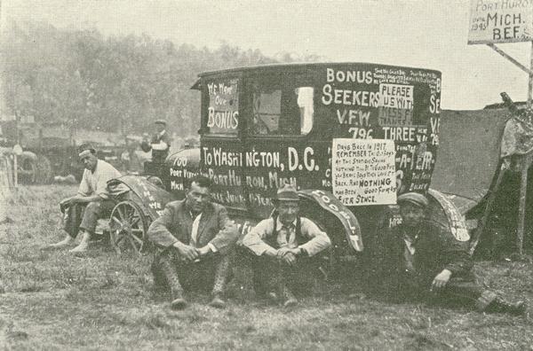 World War I veterans seated on the ground around a car with slogans painted on it such as "We Want Our Bonus" and "Bonus Seekers V.F.W. 796". They are protesting unpaid pensions as part of the so-called "Bonus Expeditionary Force" or "Bonus Army" in Washington, D.C.