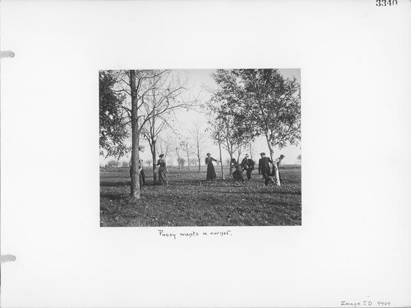 Depicts eight young men and women playing an outdoor game of pussy wants a corner.