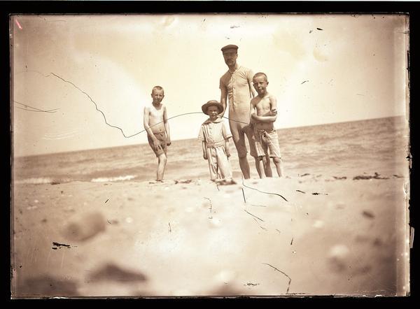 A man and three boys in swimming suits at the beach. Presumably, Lake Michigan.