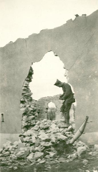 A French house in ruins.  Captioned: "Julian Bryan, standing in a hole made by a shell.  Notice that French houses are constructed for centuries where American houses are built for decades."
