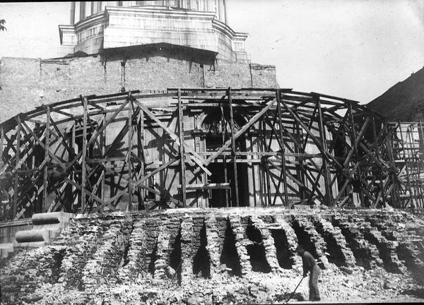 Demolition of the semi-circular West Wing of the third Wisconsin State Capitol.  In this picture the upper stories are gone, but behind the scaffolding the former entrance from State Street can still be seen.  In the foreground are the remnants of the exterior stairs.
