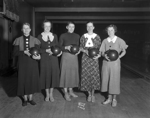 Five Charmany Dairy women bowlers, holding bowling balls at the Madison Alleys, 121 N. Fairchild. They were winners of second place in class B at the Wisconsin Women's Bowling Association tournament. Left to right: Elsa Haring, Ollie Nelson, Lorene Keefe, Dorothy Helmus and Hazel Steele.
