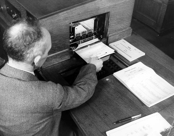 An assembly clerk withdrawing the record of a vote from the automatic voting machine in the Assembly chamber. Madison, WI.