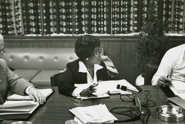 Addie Wyatt, of the United Packinghouse Worker's Association, is shown seated at a desk speaking during the Merger Talks.