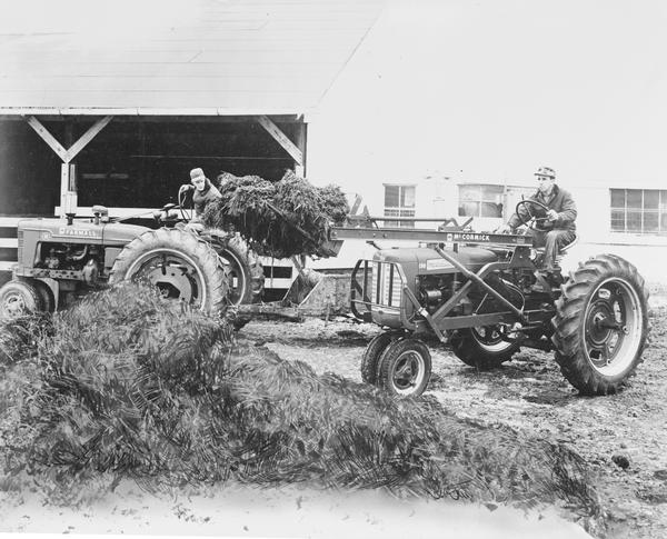 Two farmers on tractors. One of the tractors is a Farmall 230 with loader. The other is a Farmall H.