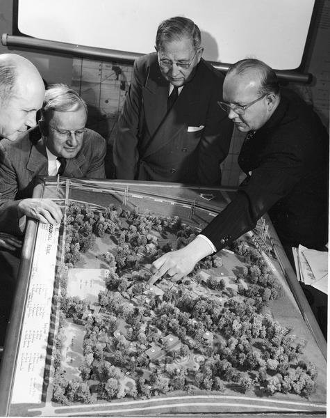 Zoo director George Speidel and members of the Milwaukee County Zoological society talking over plans for the new zoo while looking at a tentative model for the zoo.