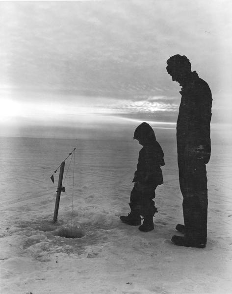 Man and boy in silhouette ice fishing on Lake Winnebago.