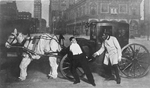 Bert Williams (right) and Leon Errol (left) are a cabbie and his fare from the 1912 Ziegfield Follies. The cab is drawn by a rumpled pantomime horse. Behind them is a painted backdrop of a New York street.