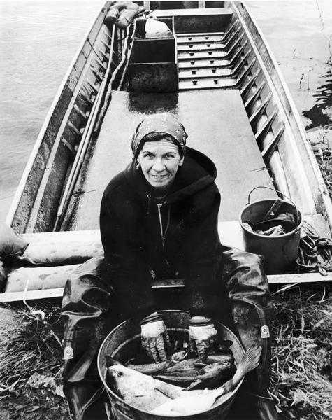 Woman in a boat showing a fish she has just caught on the Mississippi River.