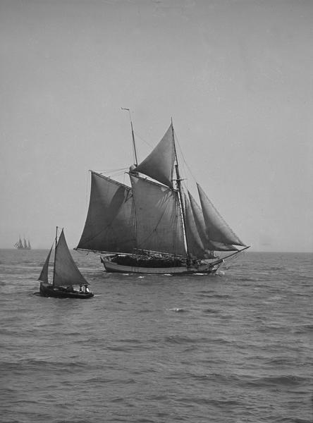 A view from the mouth of the harbor towards a large sailing ship and a smaller sailing boat.