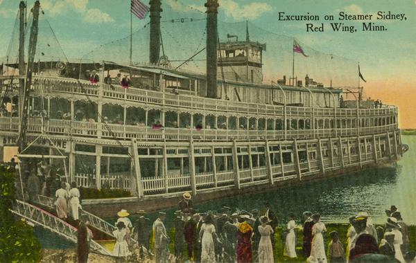The sternwheel excursion, "Sidney," loading passengers at Red Wing. The gangplank is lowered and passengers are on deck and on the landing. Later named Washington.
