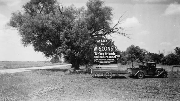 A movable billboard aimed at passing motorists along State Highway 20 in Illinois.  It reads "Relax in Wisconsin, Where Friends and Nature Meet."  Although tourists traveled to Wisconsin by train during the nineteenth century, the advent of personal automobiles greatly expanded the tourist sector of the economy.  This billboard was sponsored by Wisconsin's Conservation Department which was then responsible for state tourism promotion.