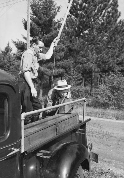 Forest rangers using an emergency phone on the back of a truck.